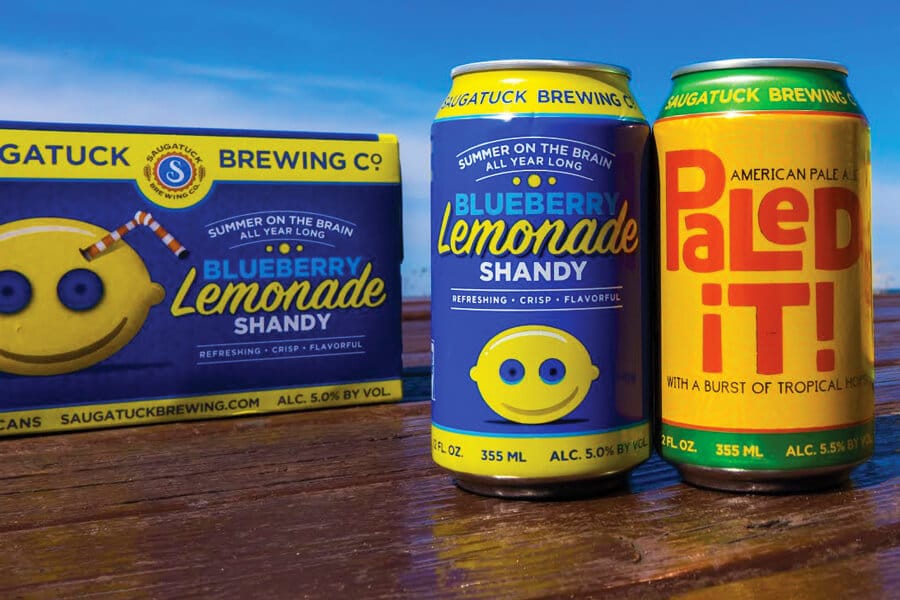 Saugatuck Brewing Company Blueberry Lemonade Shandy and Paled It Can Designs outside on a wooden table