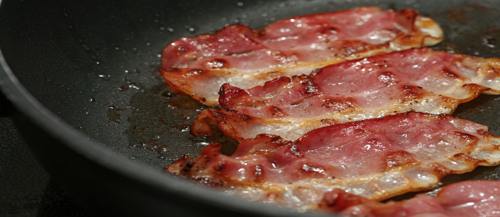 Bacon being fried in a pan.