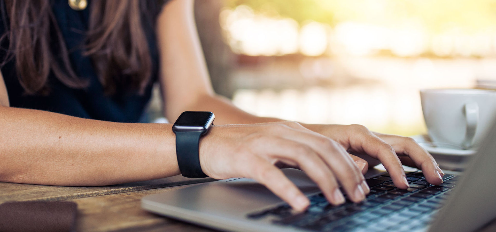 Woman wearing smartwatch using laptop computer.