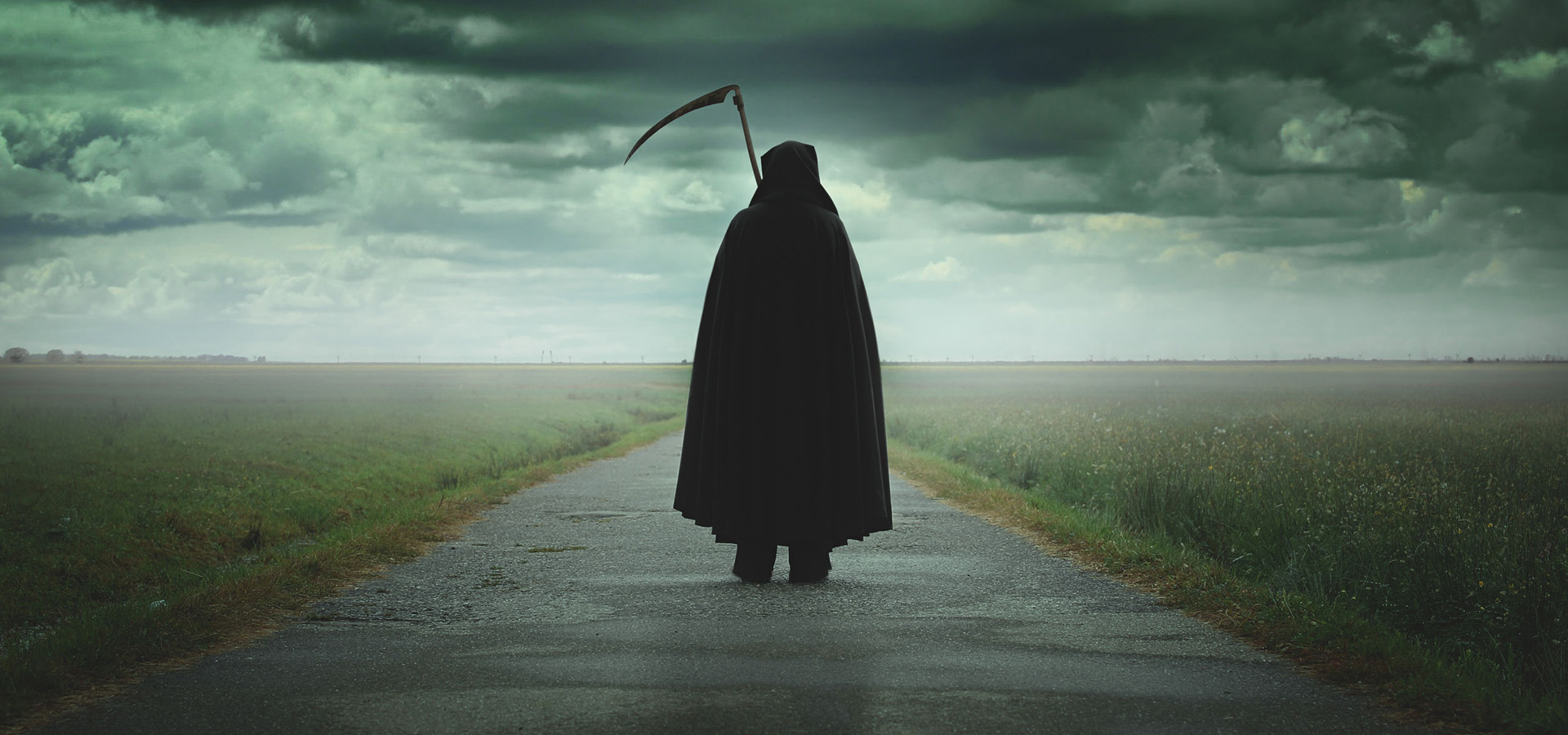 Grim reaper walking on a dark desolate road
