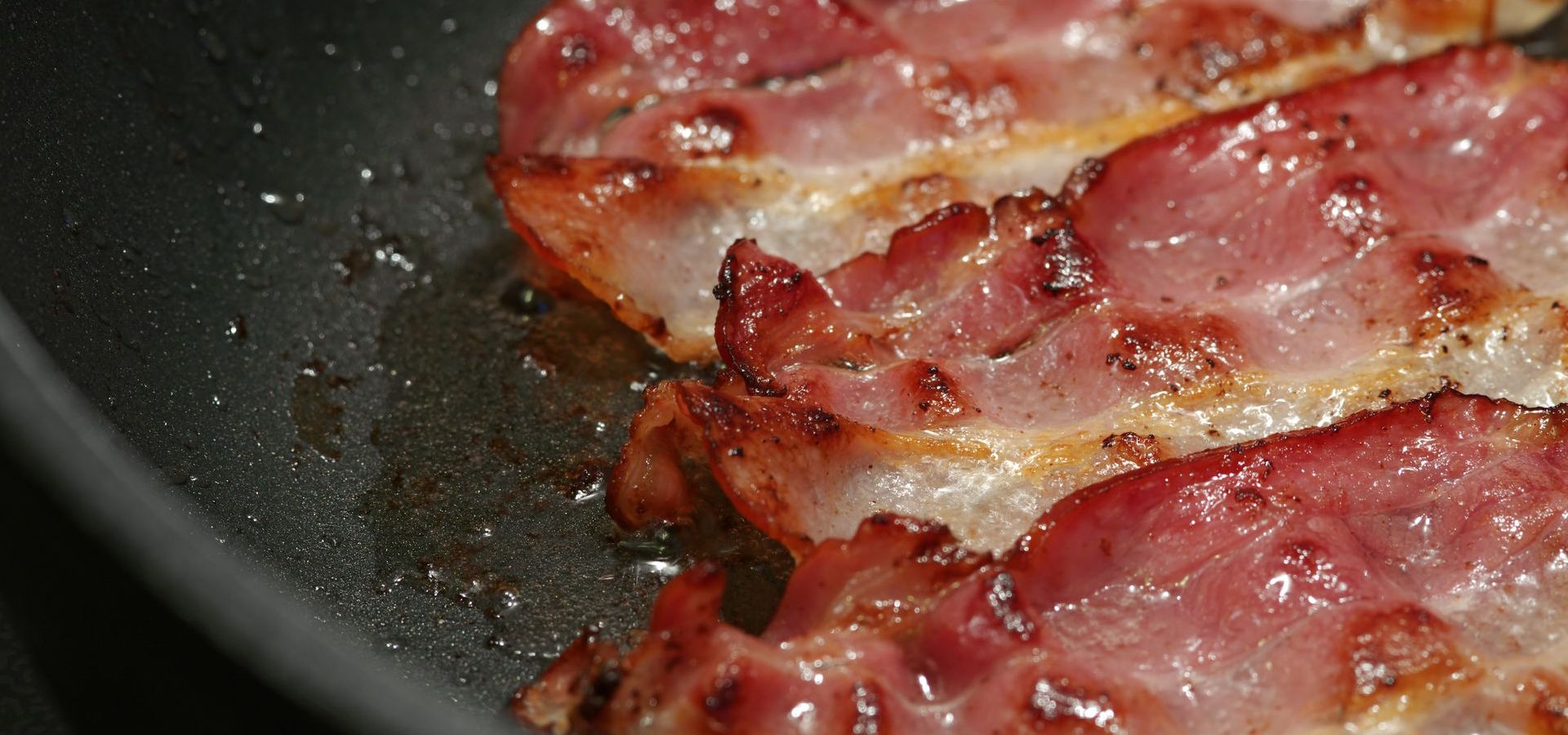 Bacon being fried in a pan.