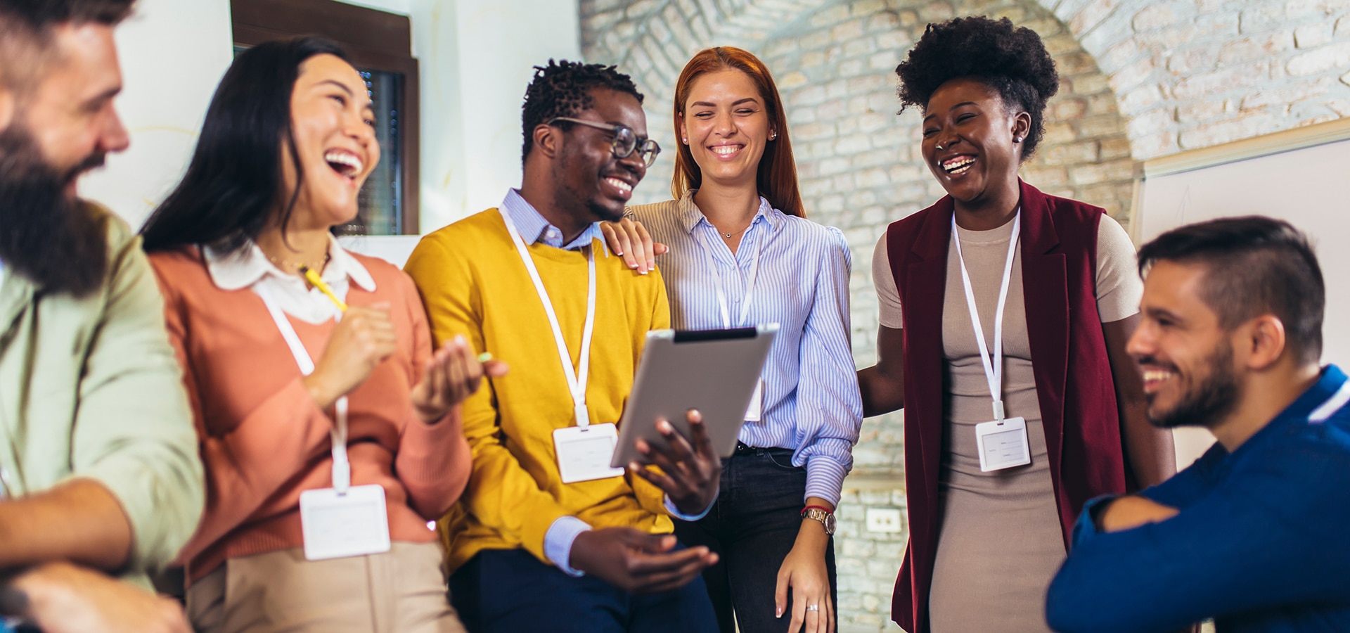 A diverse group of employees at a professional organization are laughing together.