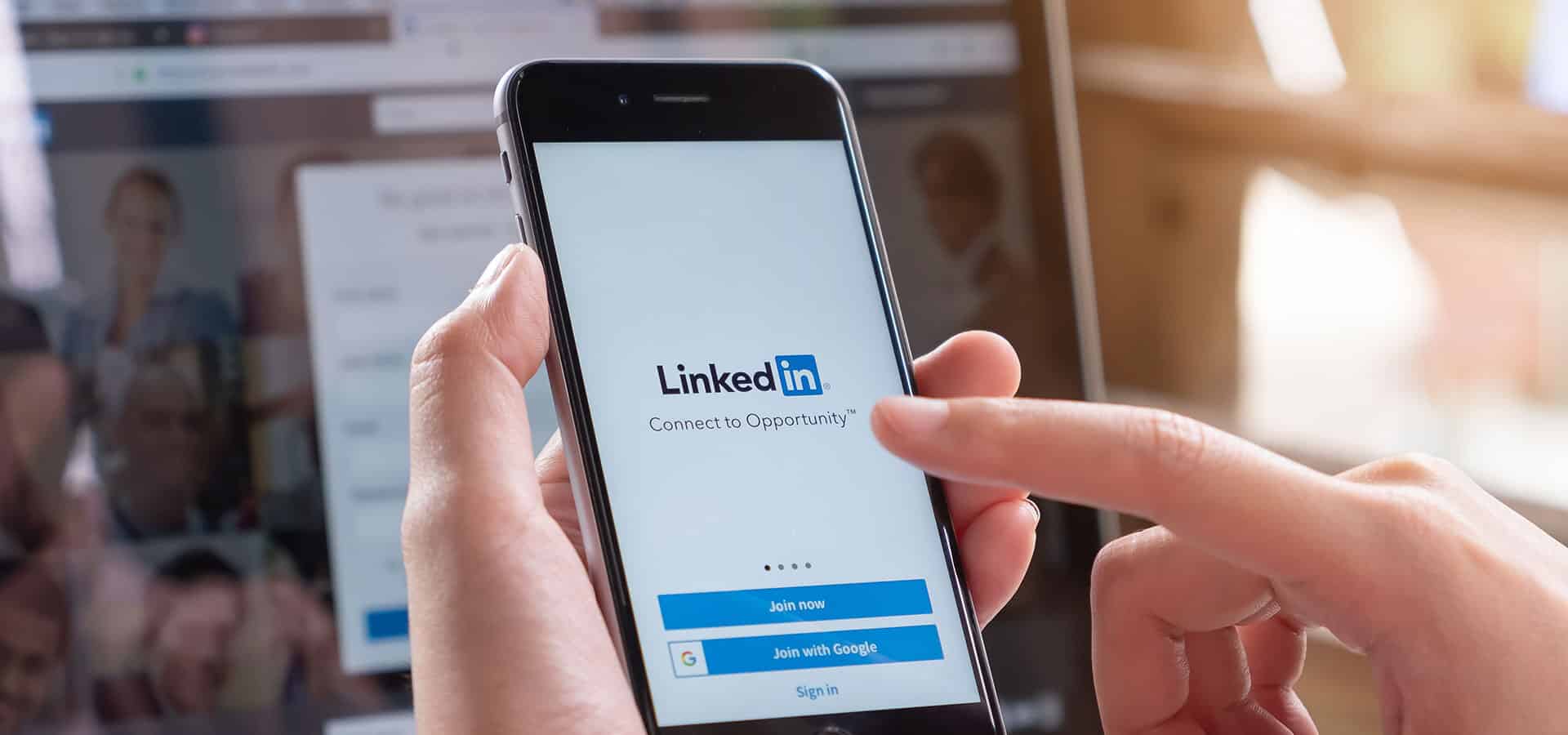 A candidate researches a company leader on LinkedIn from their phone and laptop.